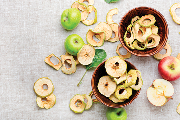 Sun-dried apple slices or apple chips and fresh apple. Dehydrated apples chips