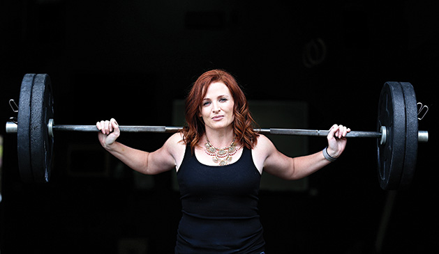 A woman holds a barbell in a photo shoot for BearFitness about empowering women.