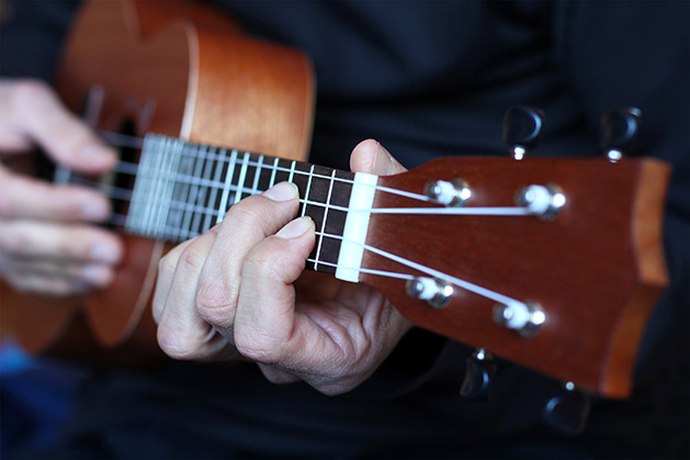 A man strums a ukulele.