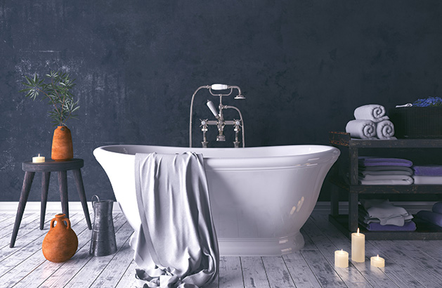 A soaker tub sits in a newly-remodeled bathroom surrounded by candles, towels and other bathroom items.