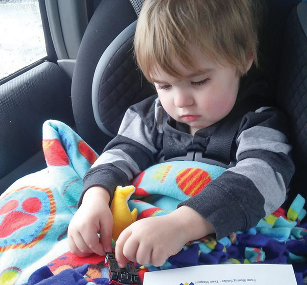 A Sharing Smiles recipient, Atticus,  enjoys the package’s contents.