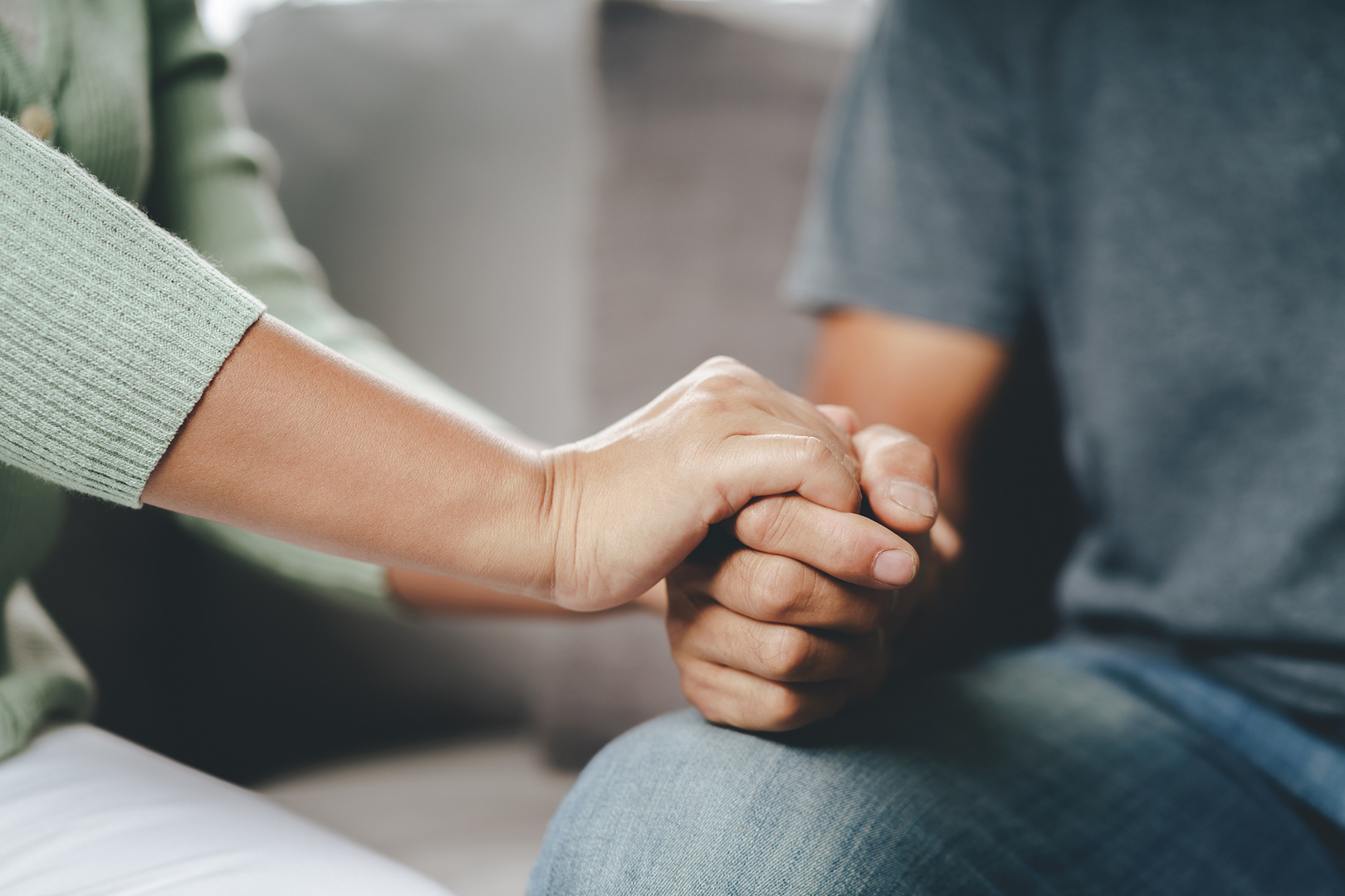 Female friend or family sitting and hold hands during cheer up to mental depress man, Psychologist provides mental aid to patient. PTSD Mental health concept